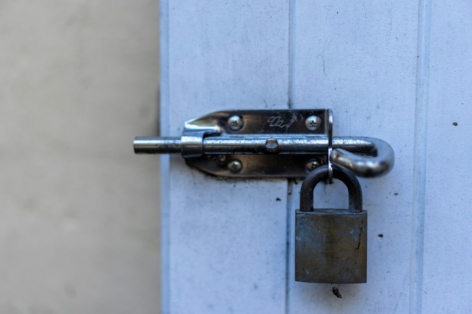 silver pad lock on white door